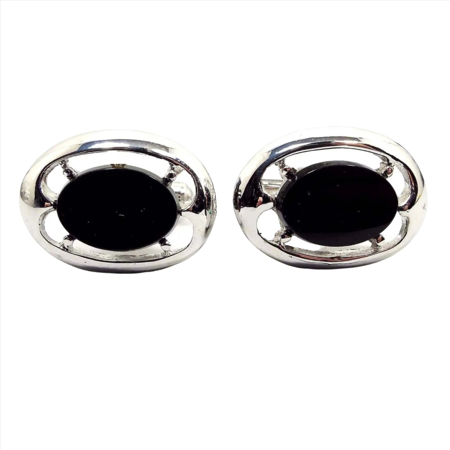 Front view of the retro vintage black and silver tone cufflinks. They are oval in shape. The middle has black glass cabs with a cut out style design around them.