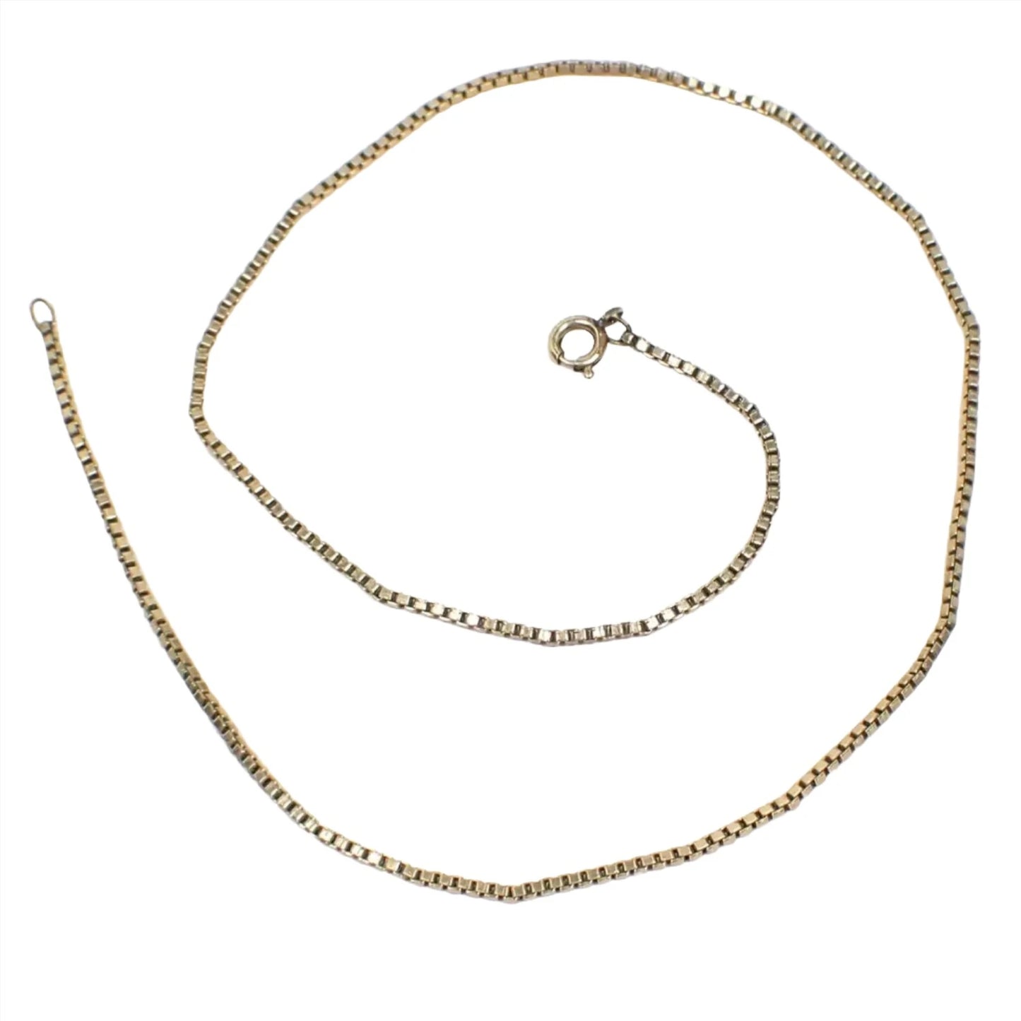 Top view of the Avon retro vintage box chain necklace. It is gold filled and a darker shade of gold in color. It has a box square cube link design and has a spring ring clasp at the end. The chain is a daintier chain that is thinner in width.