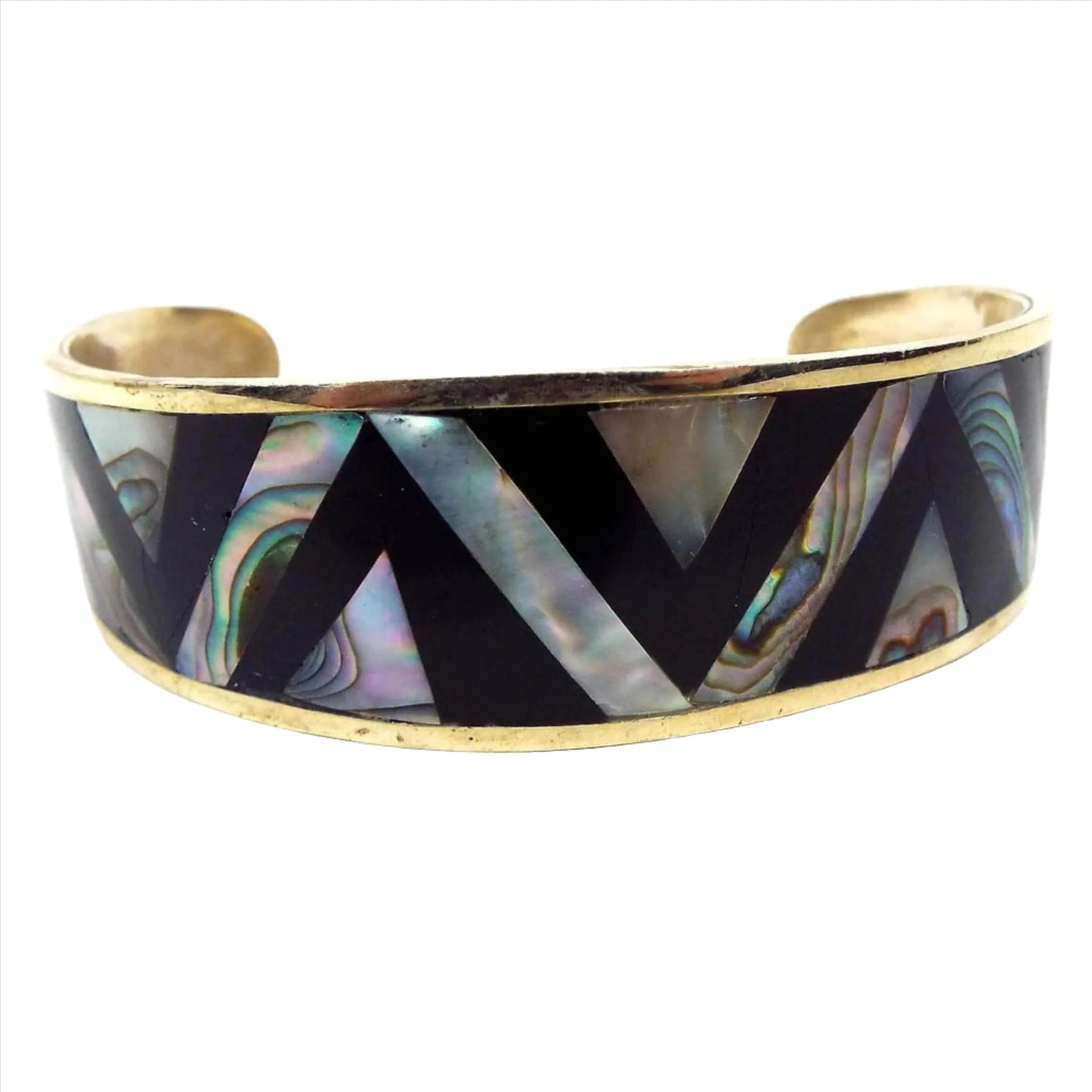 Front view of the retro vintage Mexican chevron cuff bracelet. It is a light gold tone in color with black enameled chevron patter with angled rows of abalone shell in between.