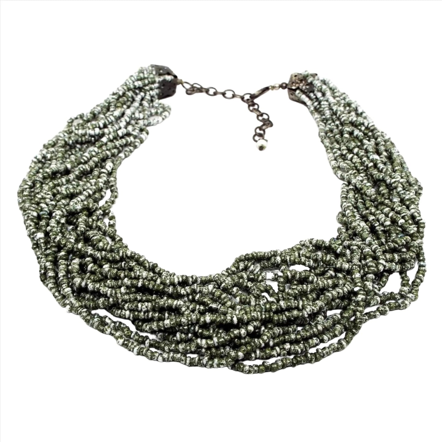Front view of the retro vintage seed bead necklace. There are numerous strands of olive green and white speckled style seed beads. The end of the necklace has an antiqued bronze color chain and lobster claw clasp.