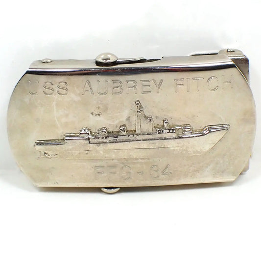 Front view of the retro vintage Aubrey Fitch belt buckle. It is silver tone in color and shows an area on the side where the slide holds the belt in place after you slide it through the buckle. The front has a depiction of the ship and is engraved USS Aubrey Fitch at the top and FFG - 34 at the bottom.