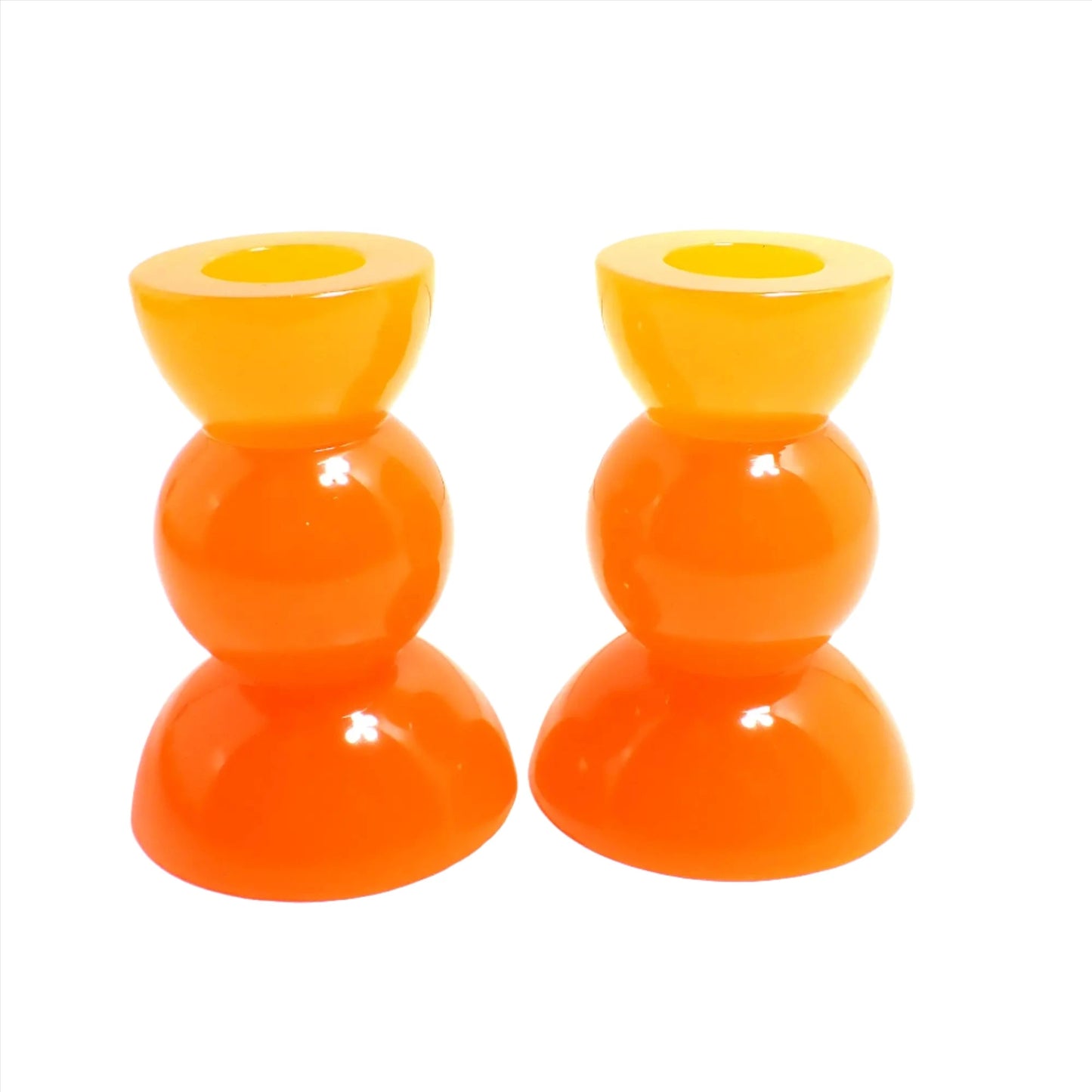 Side view of the handmade neon resin rounded geometric candlestick holders. They are neon orange in color. They are shaped with a semi circle at the top and bottom with a sphere shape in between.