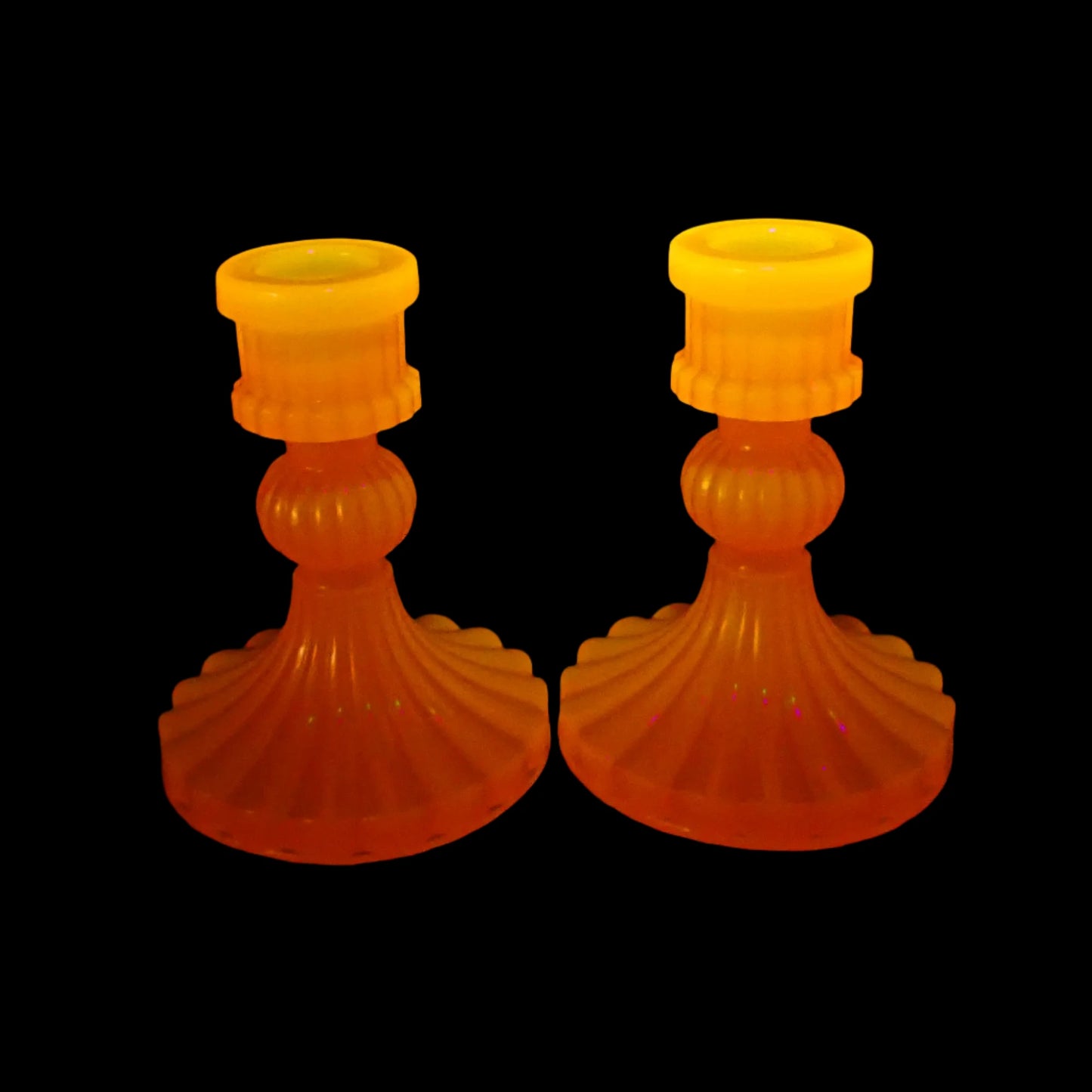 Photo showing how the vintage style handmade resin neon orange candlestick holders fluoresce under a UV light.