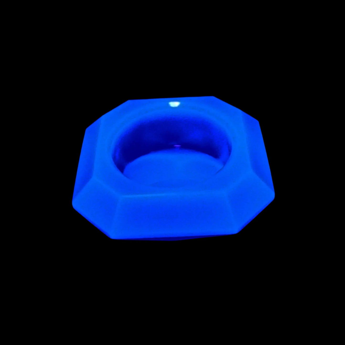 Photo showing how the neon blue handmade faceted geometric decorative bowl fluoresces blue under a UV light.