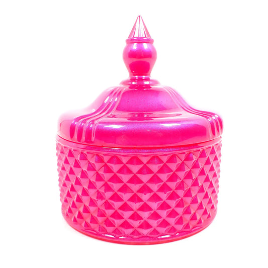 Side view of the pearly bright hot pink trinket candy dish. The bottom part has a textured bumpy diamond shaped design all the way around it. The piece itself has a rounded shape. The lid is smooth with some indented lines going down the curves as it tapers at the top. The very top of the lid has a tapered cone shape to grab onto so you can lift the lid off the trinket box.