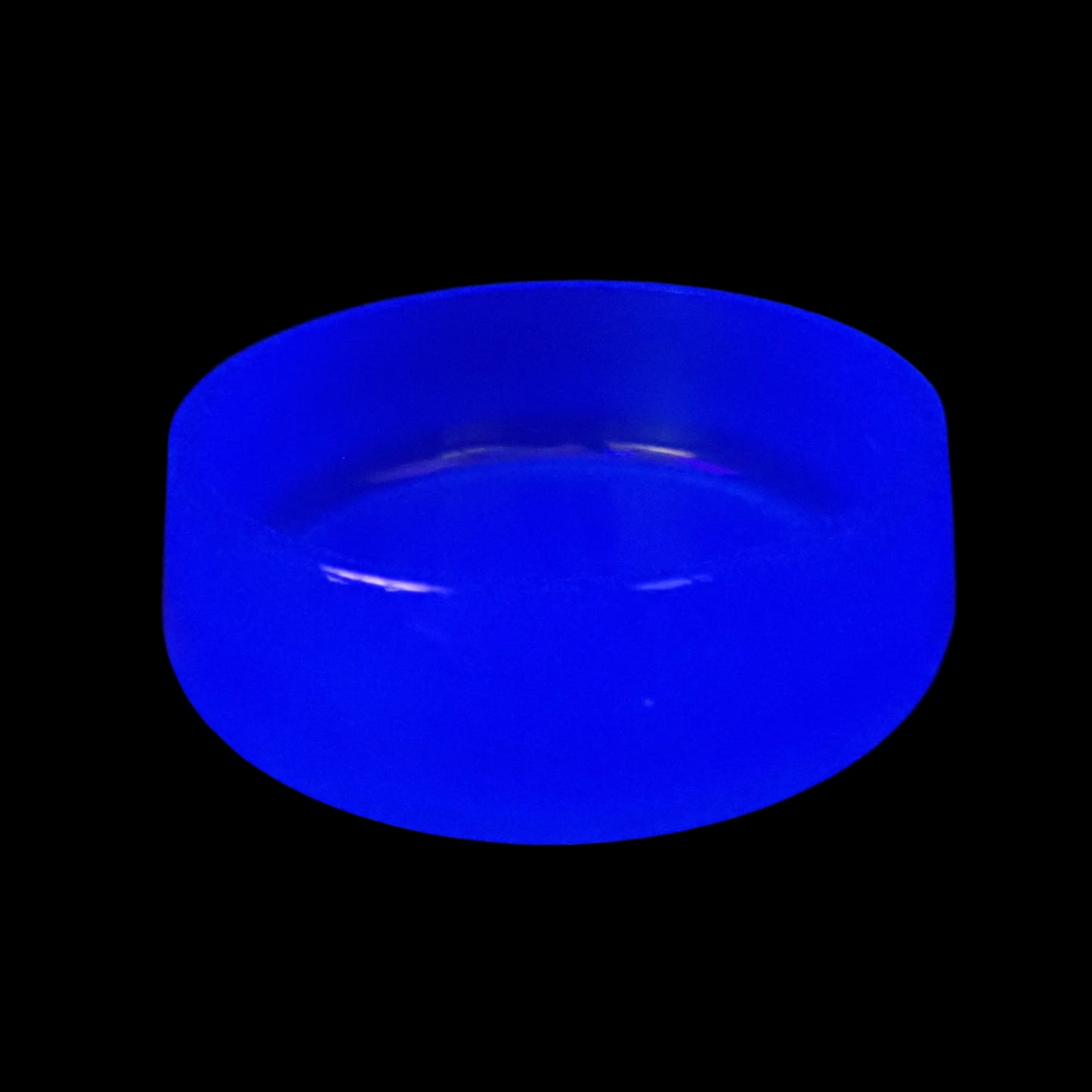 Image of the large handmade neon blue resin decorative bowl under a UV light showing that it is fluorescent and glows a bright blue color.