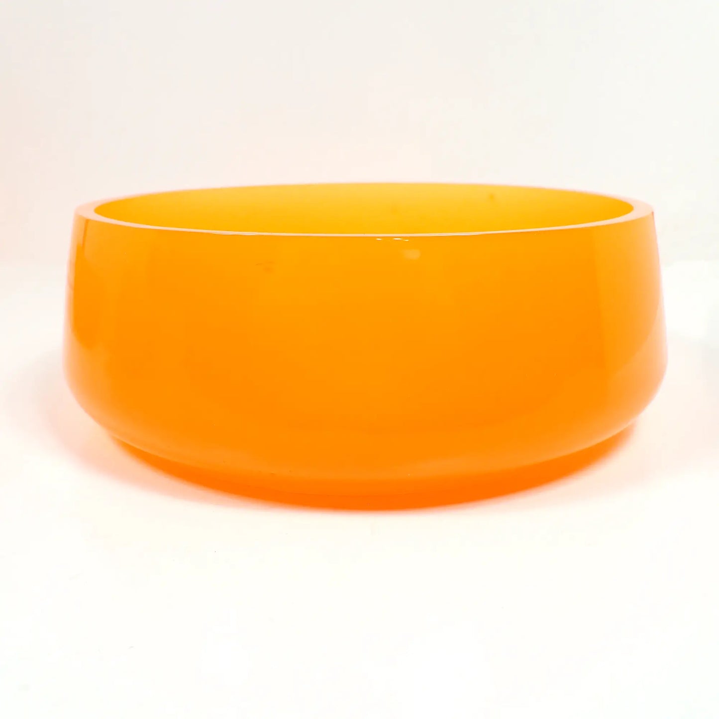 Side view of the handmade neon orange resin decorative bowl. It is round with a slight flared out bottom. The resin is shiny and semi translucent in a bright neon orange color. The top edge is flat and smooth. Great for a table centerpiece, as a succulent pot, or just to add to your fluorescent decor.