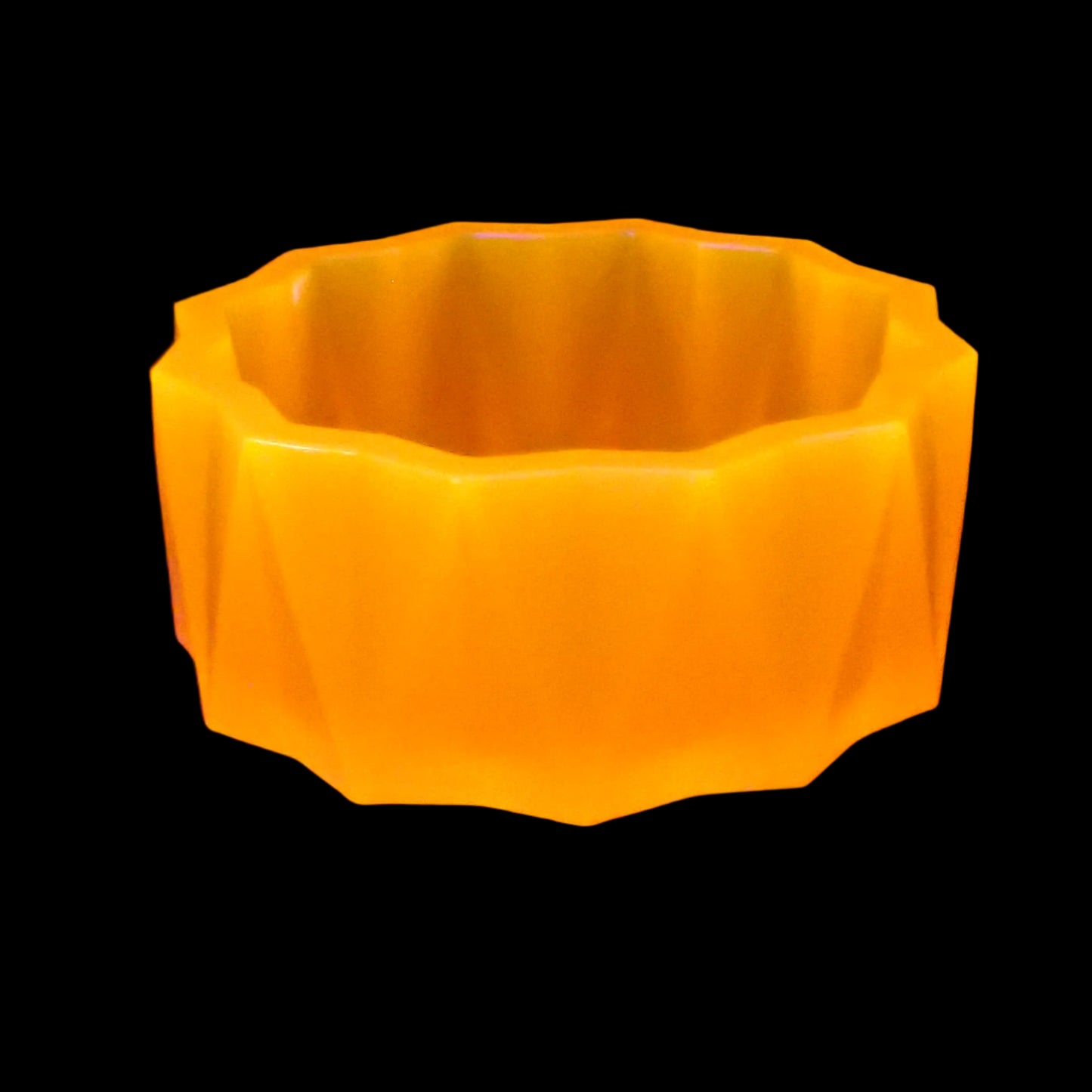 Image of the large handmade neon orange resin facted decorative bowl under a UV light to show that it is fluorescent and glows a bright orange color under the light.