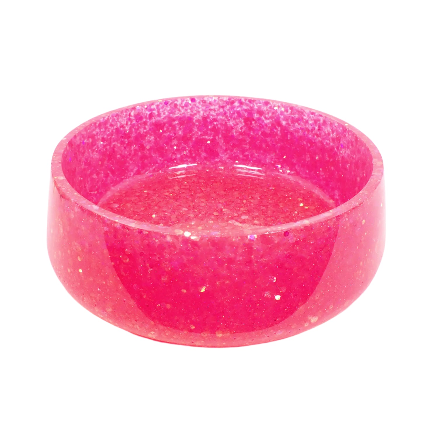 Angled side view of the large handmade pink glitter resin decorative bowl. It is round with a slightly flared bottom. The resin is shiny and semi transparent in strong lighting. The iridescent chunky glitter is throughout the entire piece.