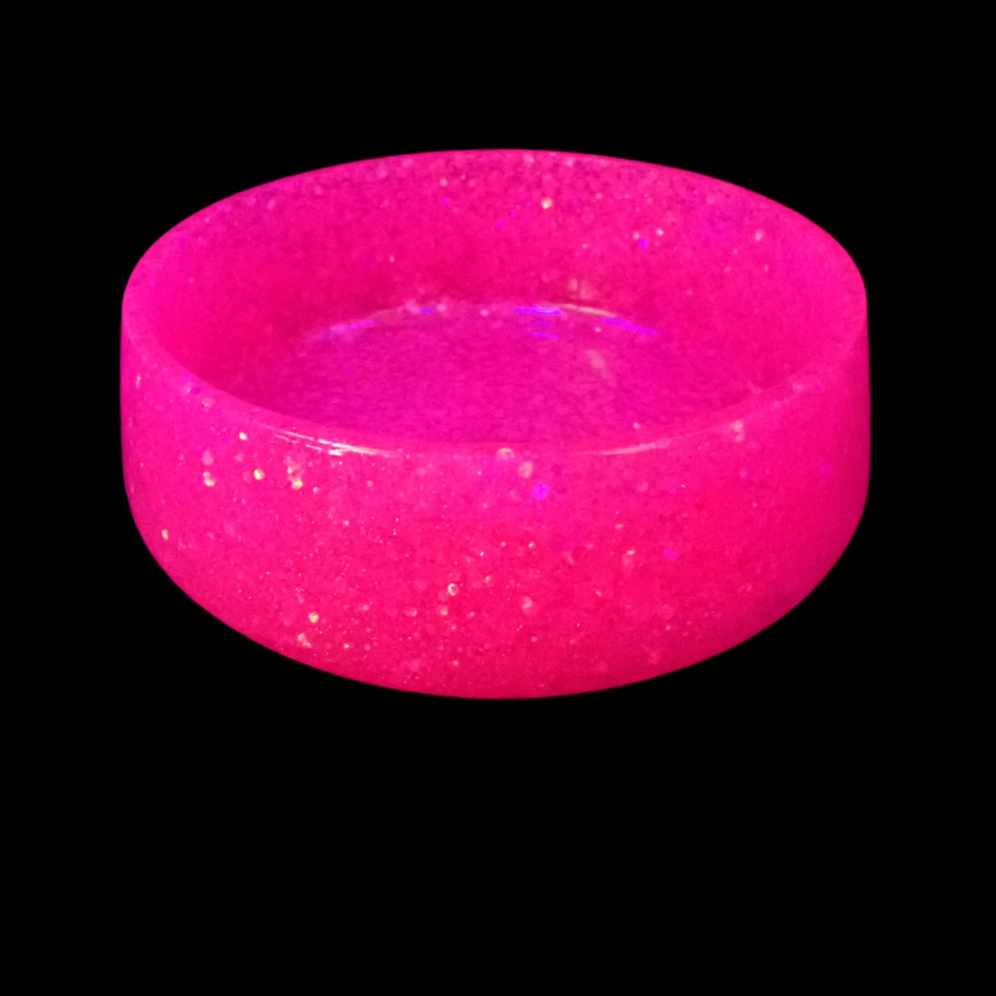 Image of the large handmade pink glitter resin bowl under a UV light to show that the glitter is fluorescent and glows a bright pink color.