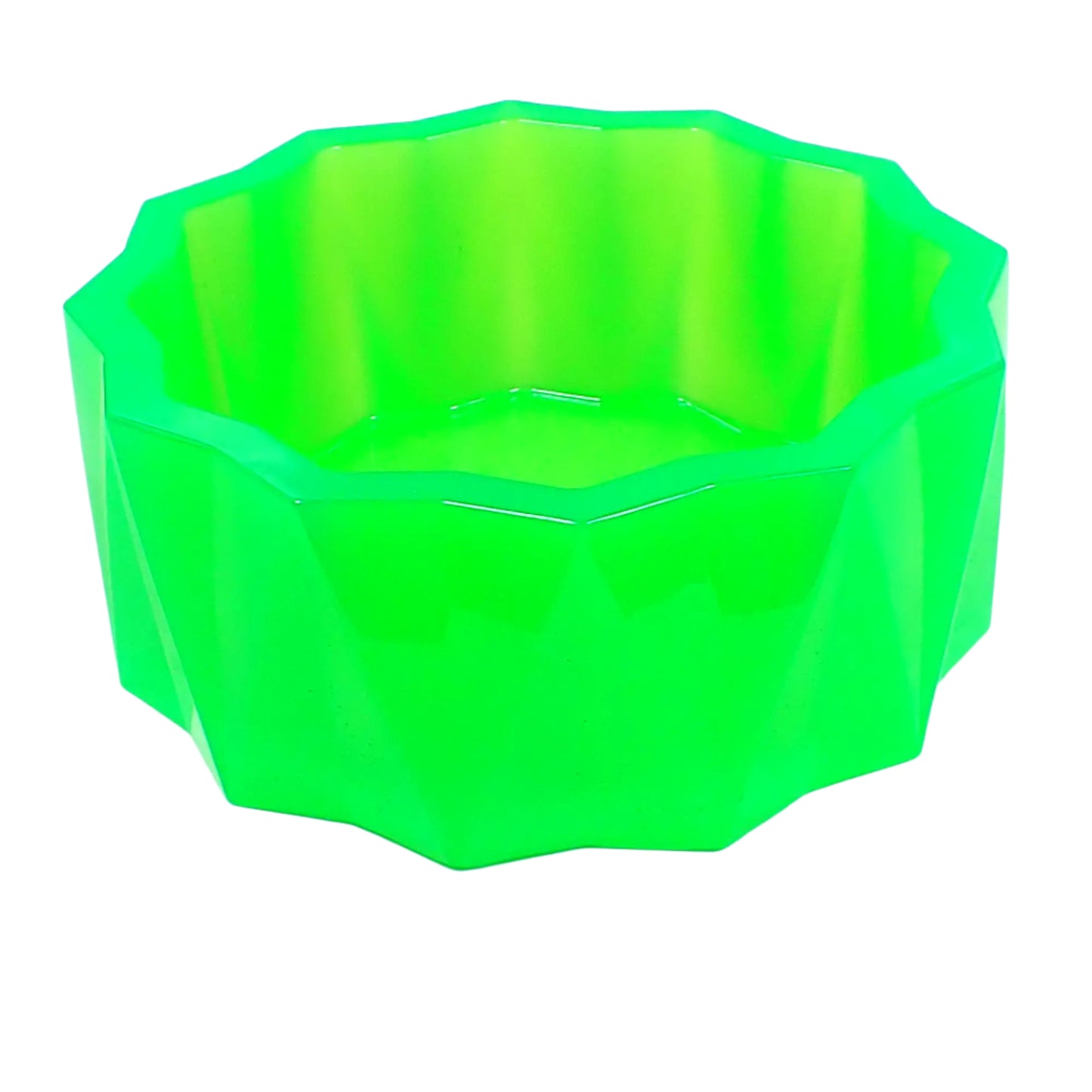 Angled side view of the large handmade neon green resin faceted bowl. The sides have a faceted triangle pattern that alternates in direction. The top of the bowl has a flat faceted sun shape design. The resin is shiny and semi translucent in a bright neon green color. Great for storing small items, as part of your table centerpiece, as a succulent planter pot, or just added to your UV fluorescent home decor.