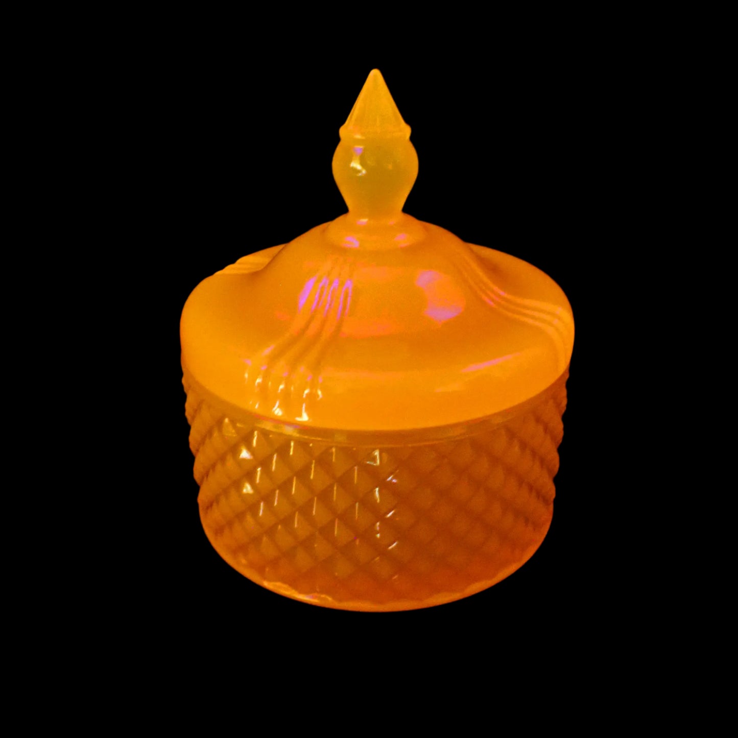 Image of the handmade neon orange resin trinket box under a UV light showing that it is fluorescent and glows a bright orange color.