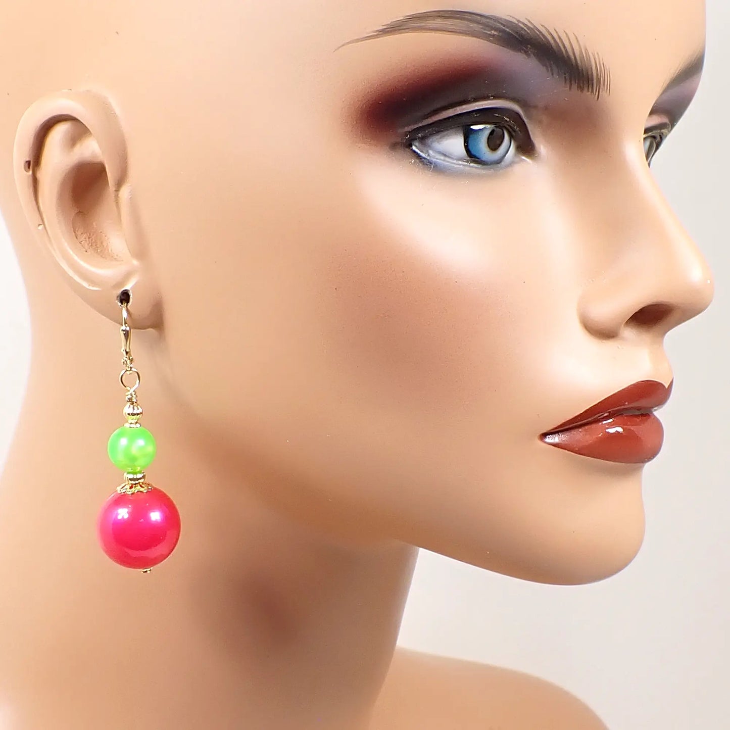 Image of the handmade neon pink and green earrings on a full sized mannequin to show how they would look worn and to give an indication of size.