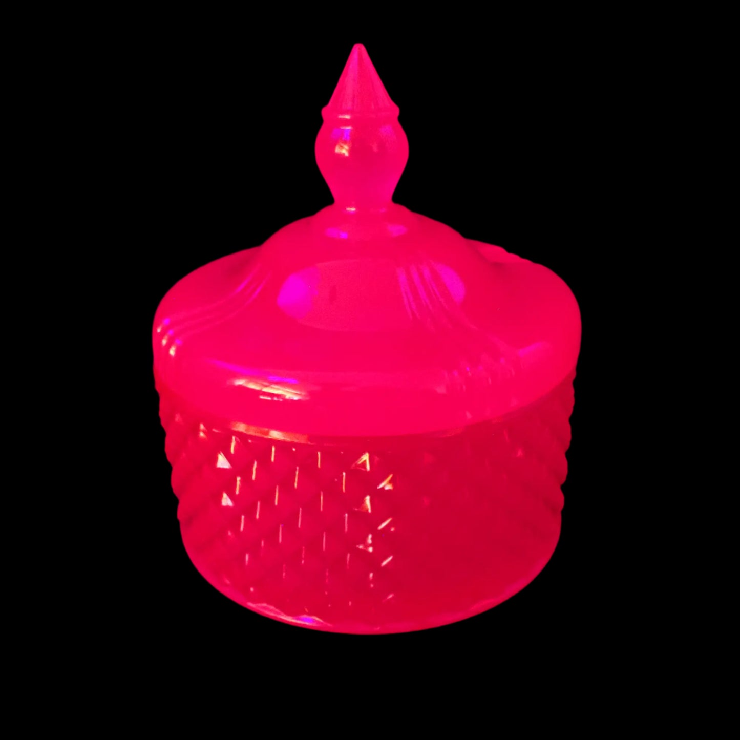 Image of the handmade neon pink resin trinket box under a UV light showing that it is fluorescent and glows a bright pink color.