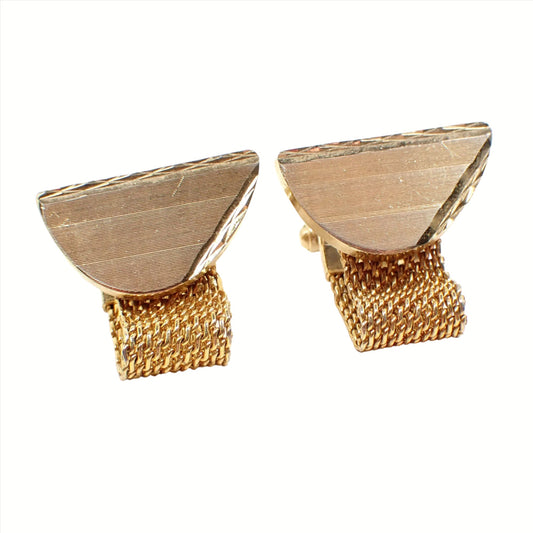 Angled view of the Mid Century vintage wrap around cufflinks. The metal is gold tone in color. There are large semi circle shapes with the flat edge at the top. The top and one side have an etched cut diamond shape pattern design. There is metal mesh coming down from the bottom that wraps around to the back.