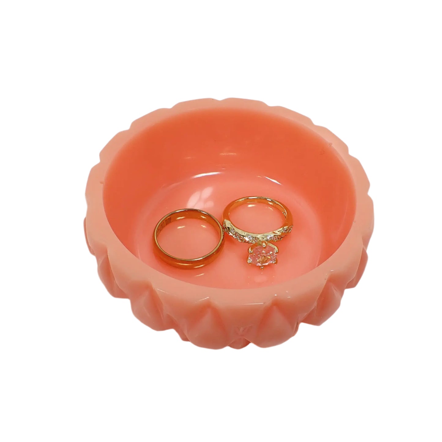 Angled view of the pastel peach resin ring dish showing a couple of display rings in it to give an indication of size.