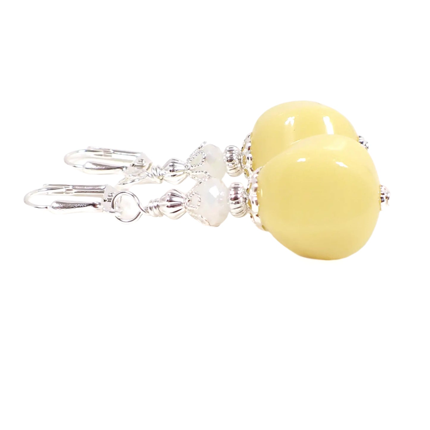 Side view of the handmade beaded nugget earrings. This image shows them with the lever back pierced components at the top though other options are available. The faceted glass beads at the top are opaque. There are vintage German acrylic beads at the bottom in a pastel yellow color.