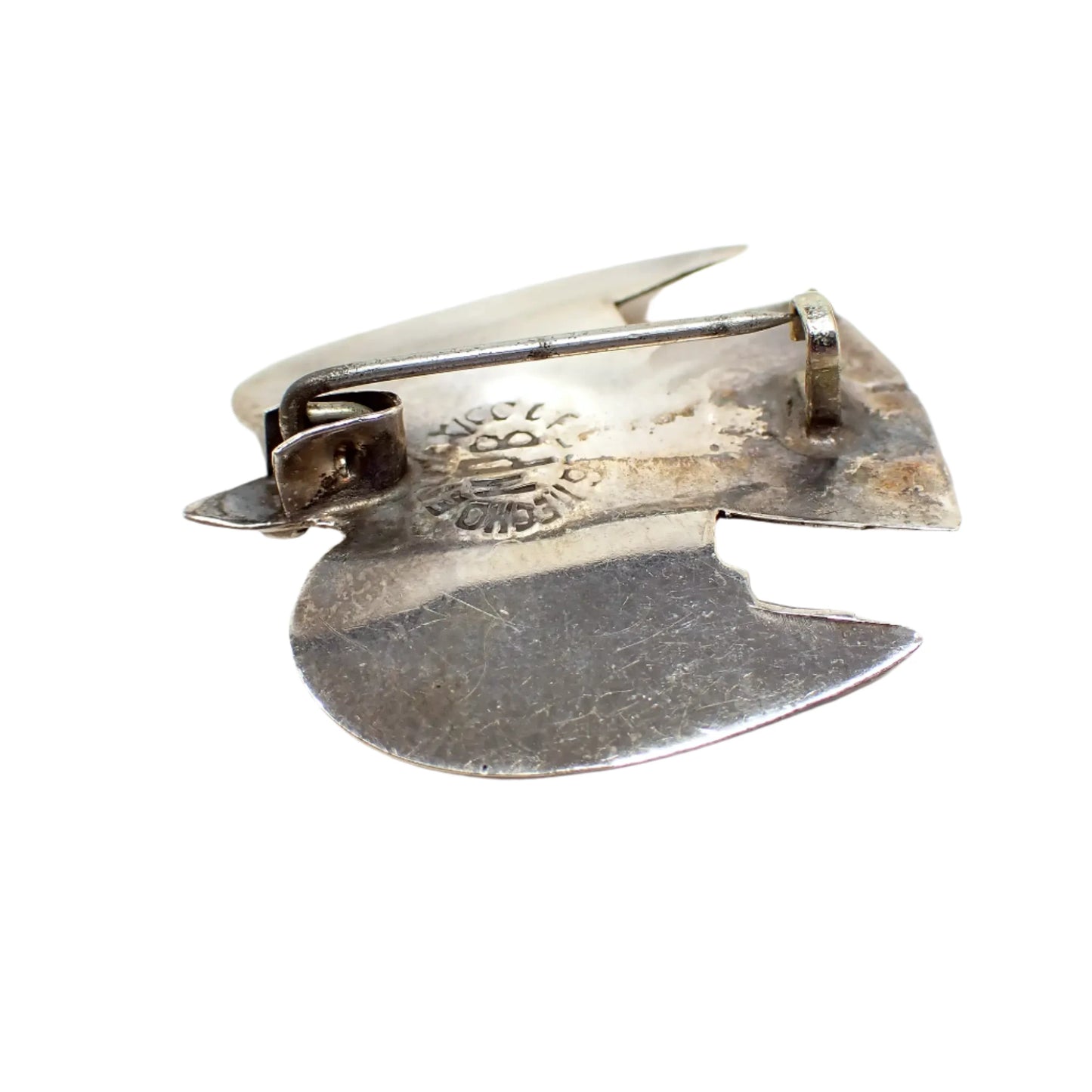 Photo of the backside of the pin. The sterling has darkened from age. The pin shows a C clasp tuck under style setting. You can see the marking Hecho en Mexico 925 MPB stamped on the back.