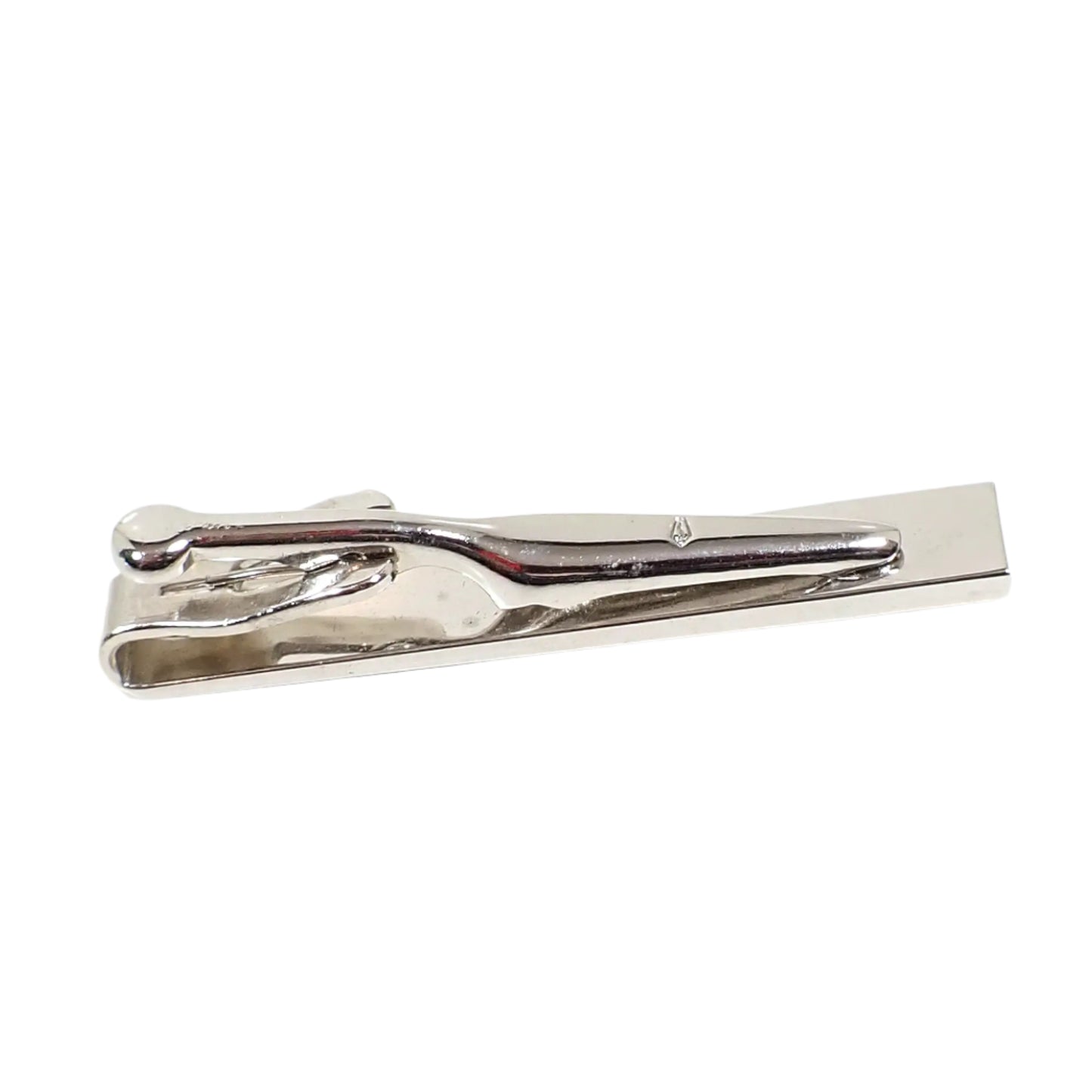 Back side view of the vintage Swank tie clip. The metal is shiny silver tone in color. There is a small Swank marking of a tie symbol with an S inside it stamped on the clip itself.