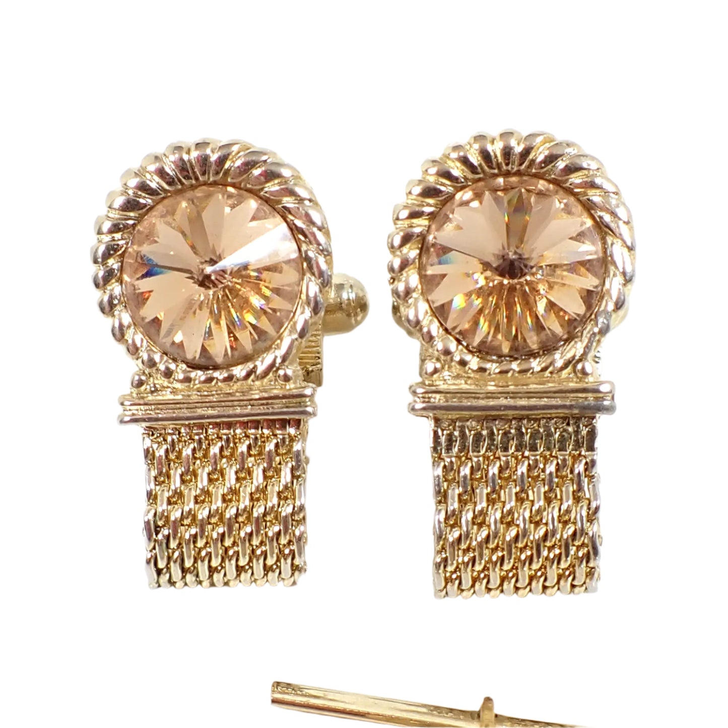Close up view of the cuff links. The tops are round with a braided rope style design around the rivoli rhinestone. The rhinestones are champagne colored and have a point in the middle going outward. There are mesh metal bands on the bottom that wrap around to the back.