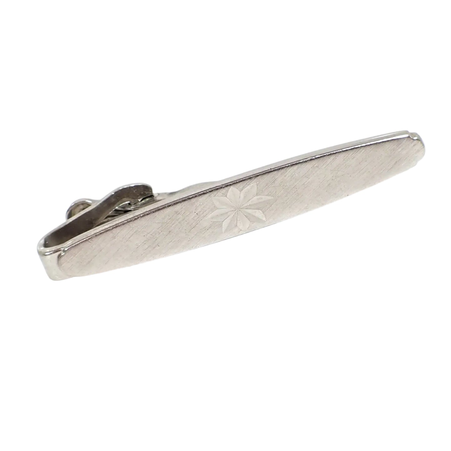 Angled front view of the Swank vintage tie clip. The front has a textured brushed matte pattern with an engraved starburst design in the middle.