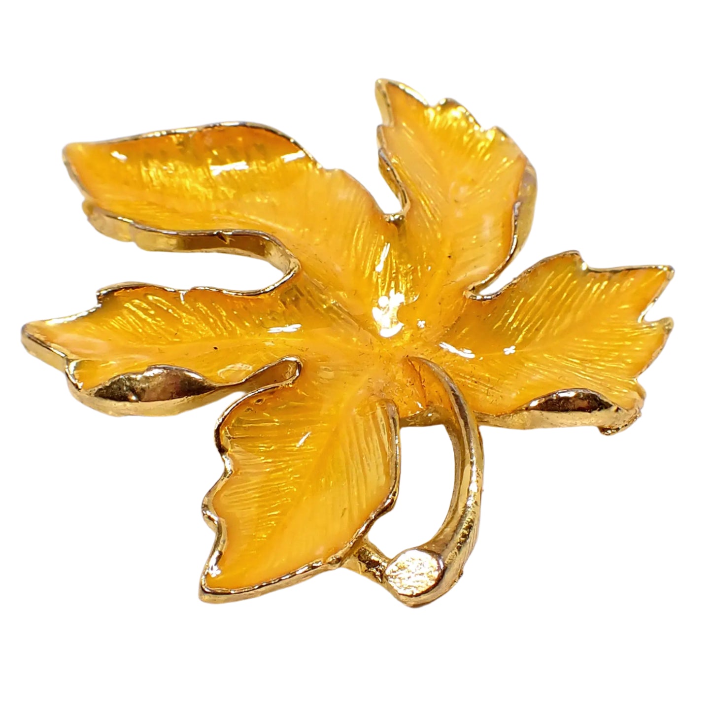 Angled front view of the brooch. Here the curled edges of the leaf can be seen where the gold tone color metal comes up over the enameled area. The detailed leaf veins are also seen through the enamel.