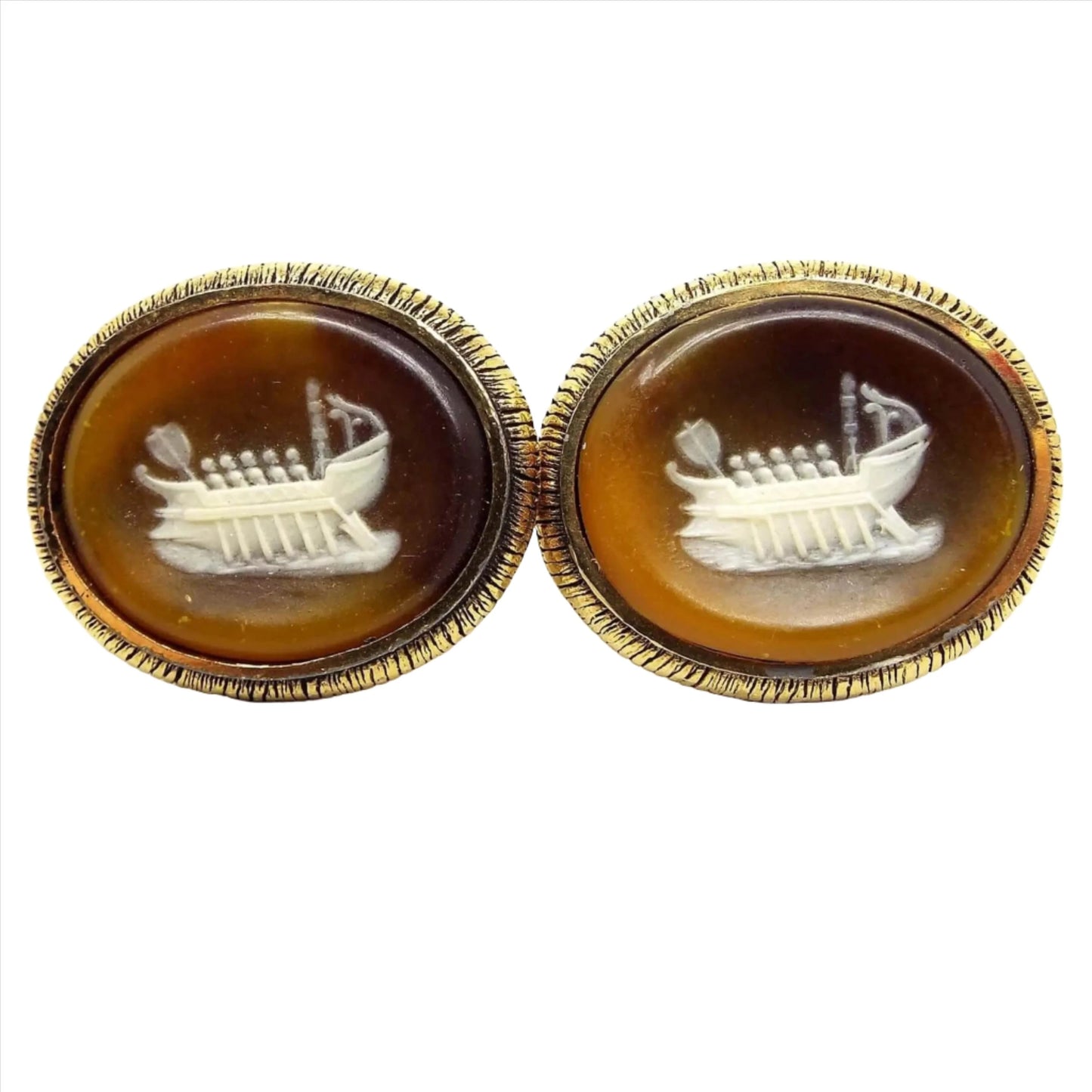 Front view of the Mid Century Vintage Dante Incolay cufflinks. The metal is gold tone in color. They are large ovals with a ship cameo on the front in shades of brown, cream, and white incolay stone.
