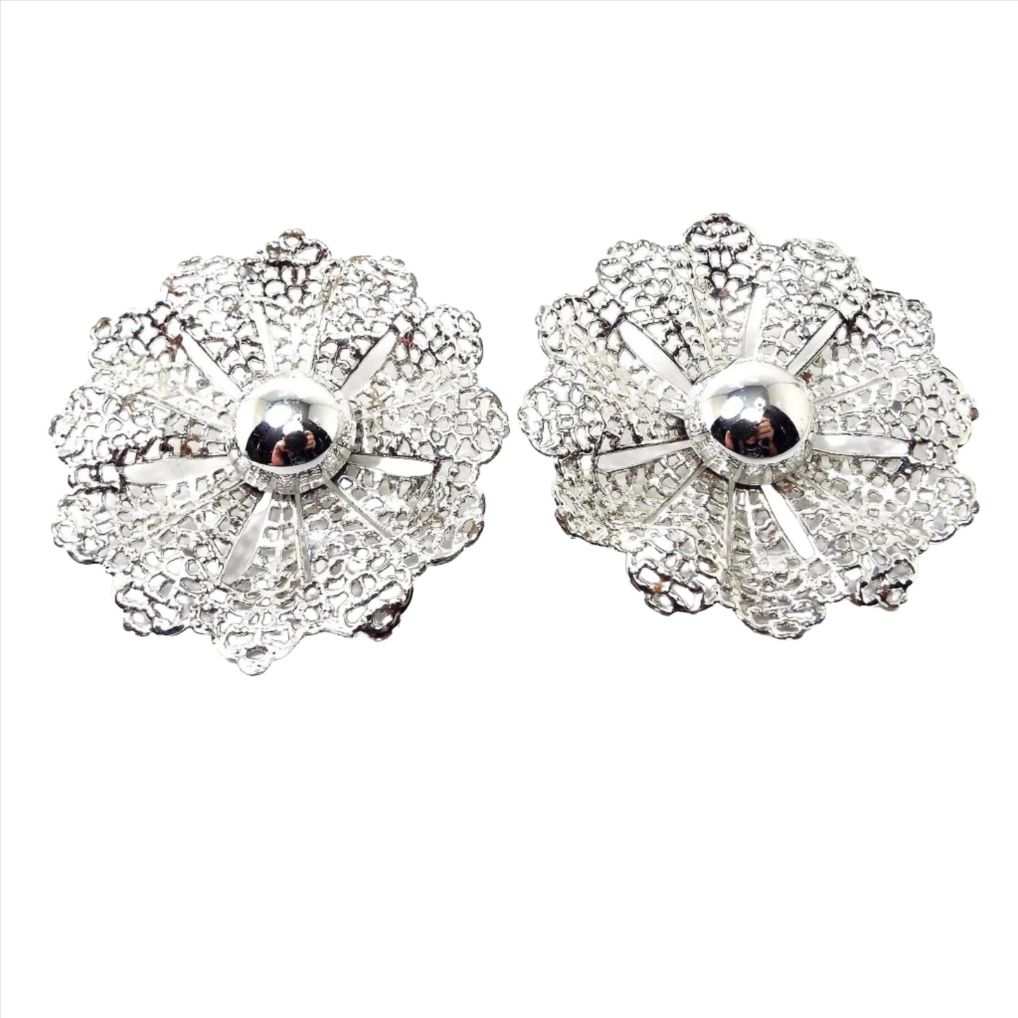 Front view of the Mid Century vintage Sarah Coventry clip on earrings. They are silver tone in color with a large filigree flower design.