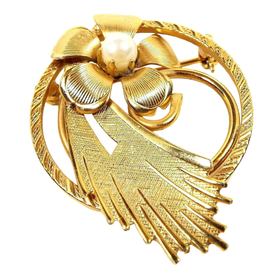 Front view of the Mid Century vintage cultured pearl brooch pin. The metal is gold tone in color and has a matte brushed and textured design. There is a circle with a fan spray design in the middle and a flower at the top. The cultured pearl is in the middle of the flower. There is a tiny spot of green verdigris underneath one petal on the front when viewed under magnification.