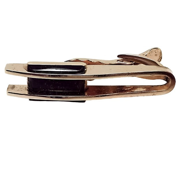 Front view of the Hickok Mid Century vintage tie clip. The metal is gold tone in color. There are two bars going horizontally with a black glass cab through the middle of them.