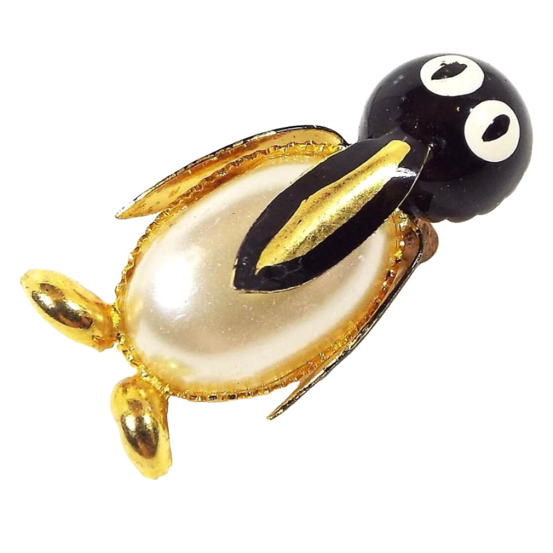 Front view of the Mid Century vintage penguin brooch pin. It has metal gold tone color and black enameled face, beak, and wings. The eyes are enameled white. The penguin's belly is a domed plastic faux pearl cab.