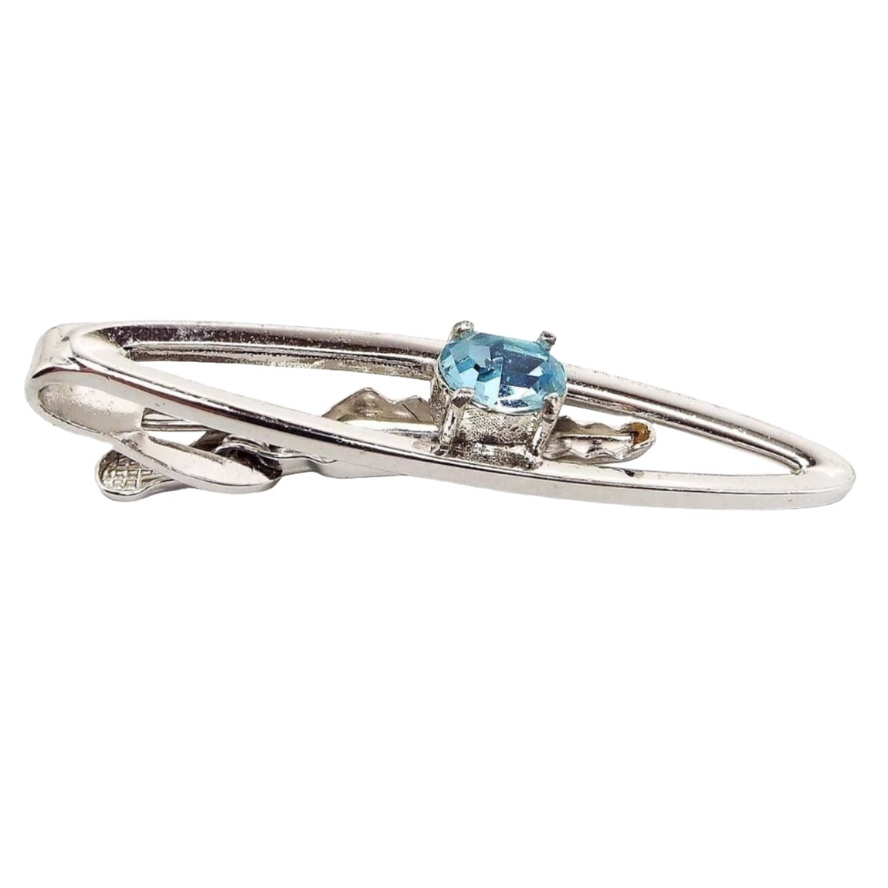 Angled front view of the Mid Century vintage Dante rhinestone tie clip. The metal is silver tone in color. It has an open long oval design with a light blue oval rhinestone in the middle. The rhinestone is prong set.