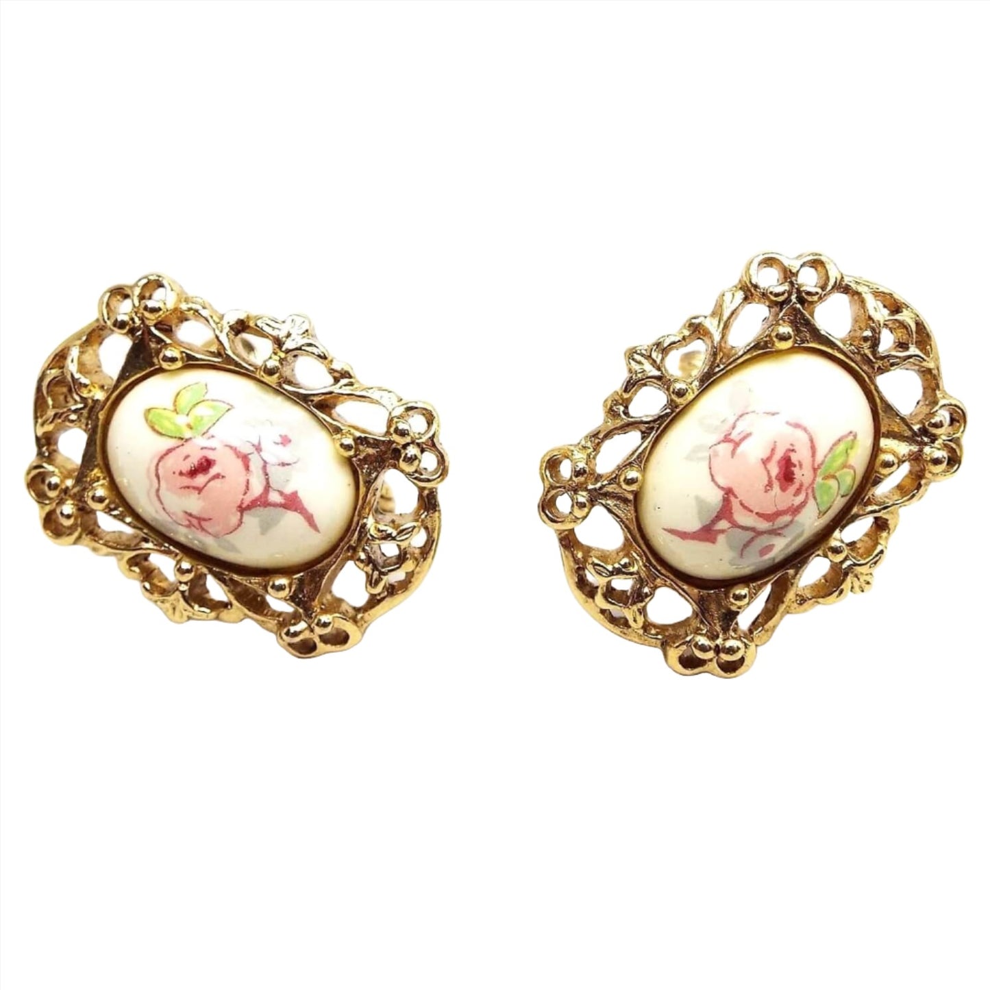 Front view of the retro vintage floral clip on earrings. The metal is gold tone in color and there is a filigree setting around a plastic oval cab in the middle. The cabs have decals with pink rose flowers on them.