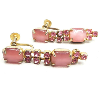 Front view of the Mid Century vintage rhinestone screw back earrings. The metal is gold tone in color. There is a rounded rectangle pink glass faux cat's eye stone at the top with two rows of small round pink rhinestones coming down from it, another rounded rectangle pink faux cat's eye stone and three more pink rhinestones at the bottom. 