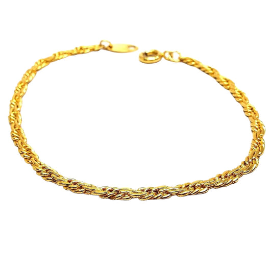 Angled view of the retro vintage Trifari chain bracelet. It is gold tone in color with a twisted rope chain design. There is a spring ring clasp at the end.