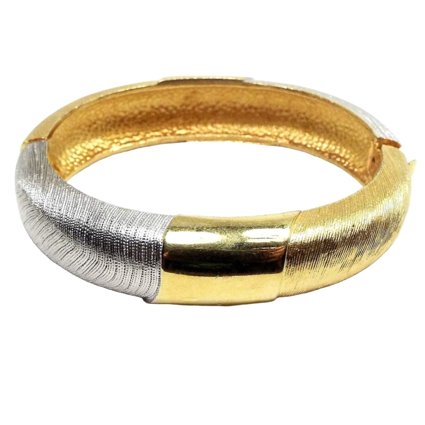 Angled side view of the retro vintage hinged bangle bracelet. It is two tone in color with gold tone and silver tone color metal. Most of the bangle has a textured line design on it. There is a locking hinge clasp at the side.