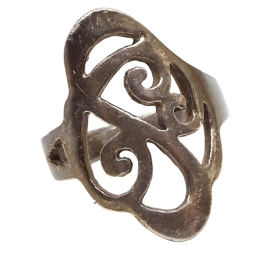 Front view of the retro vintage sterling silver filigree ring. The silver is darkened from age. There is a cut out curl design on the top. The filigree part is fairly wide with rounded corners.