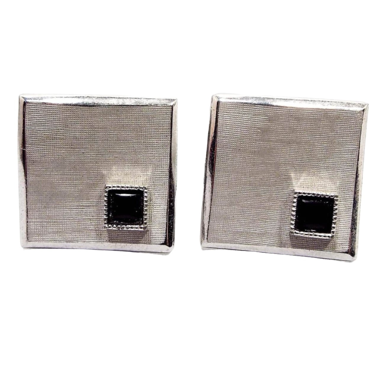 Front view of the Mid Century vintage Swank wavy cufflinks. They are brushed matte silver tone in color. There are small square black glass cabs on one corner. The cufflinks are square shaped but have an abstract wavy style design.