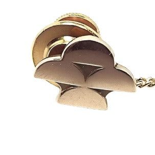 Front view of the Mid Century vintage OCT OC Tanner tie tack. It is gold tone in color. The 10K gold front has four half moon shapes with one on top, one on the bottom, and two in the middle. The gold plated clutch is a bit brighter gold tone and has a chain attached.