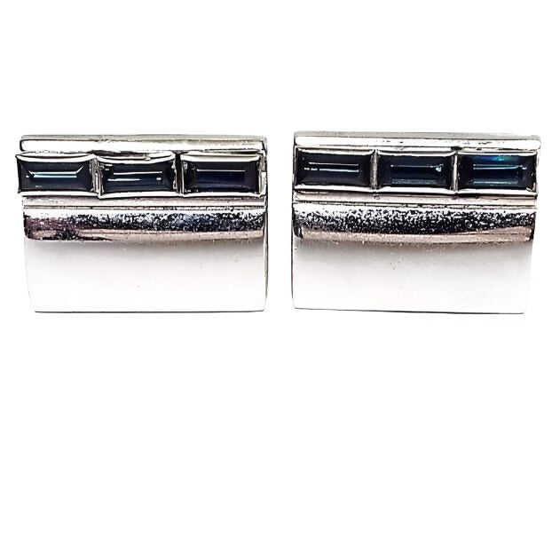 Front view of the Anson Mid Century vintage rhinestone cufflinks. They are silver tone in color and rectangular in shape. There is a row of 3 baguette rectangle cut blue rhinestones at the top of each cufflinks.