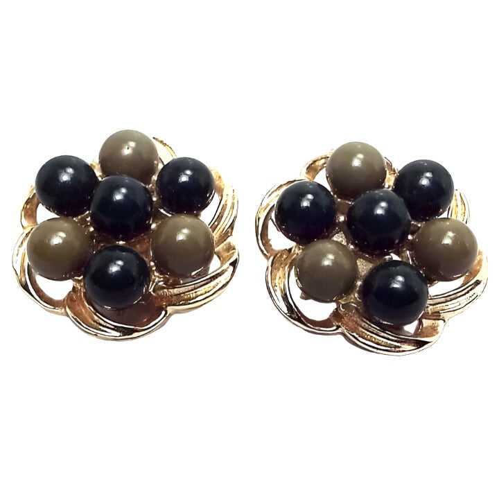 Front view of the Mid Century vintage clip on earrings. The metal is gold tone in color. Each earring has a scalloped open floral like design. There are round beads around the edge alternating between dark green and olive green in color and another dark green bead in the middle.
