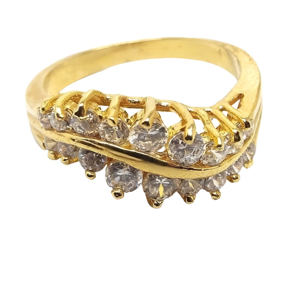 Angled top and side view of the retro vintage cubic zirconia cocktail ring. The top has a curved wavy design. There are two rows of CZ stones that are graduated in size from largest in the middle to smaller at the ends. All are prong set and sparkling clear in color. The setting and curvy metal band between the stones is plated gold tone in color.