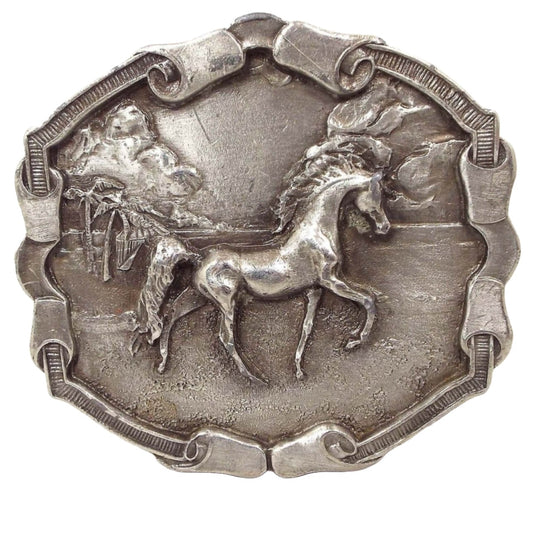 Front view of the retro vintage Bergamot Brass Works horse belt buckle. The metal buckle is pewter with varying shades of gray. The scene is a detailed raised 3D like design of a prancing Arabian style horse along the beach. There are palm trees, clouds, a sandy beach area, and very small waves in the background. The edge of the buckle is textured with small lines and has curled ribbon like areas on the top, bottom, and sides.