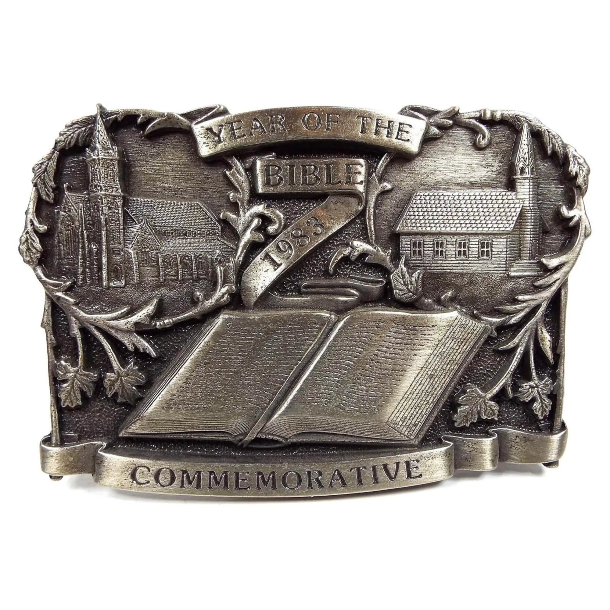 Front view of the retro vintage Bergamot Bible commemorative belt buckle. It says Year of the Bible 1983 and has a depiction of two churches and an open bible on it. It is pewter gray in color.