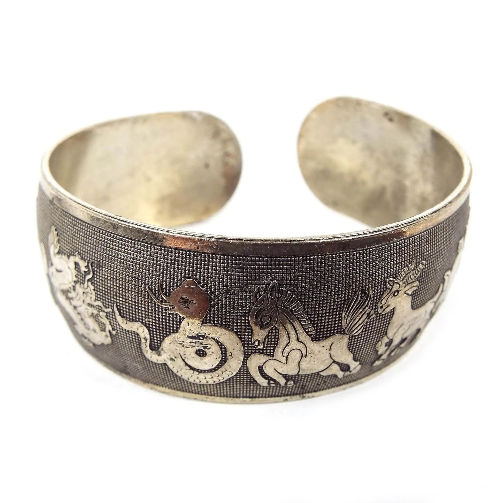 Front view of the retro vintage Chinese zodiac cuff bracelet. It is antiqued silver tone in color and has depictions of the Chinese Zodiacs across the outside edge.