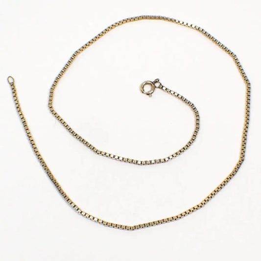 Top view of the Avon retro vintage box chain necklace. It is gold filled and a darker shade of gold in color. It has a box square cube link design and has a spring ring clasp at the end. The chain is a daintier chain that is thinner in width.