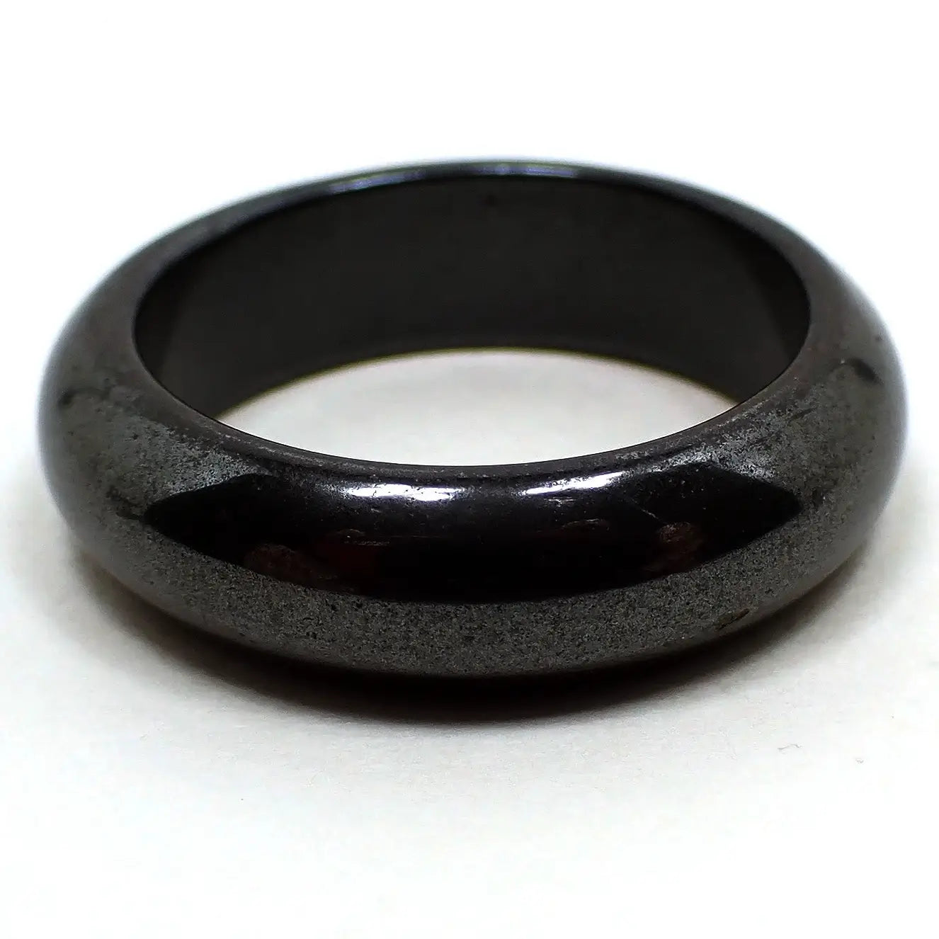 Enlarged side view of the retro vintage hematite band ring. It is dark metallic gray in color and has a rounded edge. 