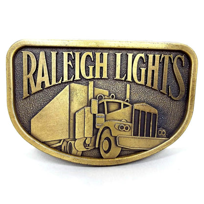Front view of the retro vintage Raleigh Lights belt buckle. It is antiqued brass in color and has a semi truck on the front.