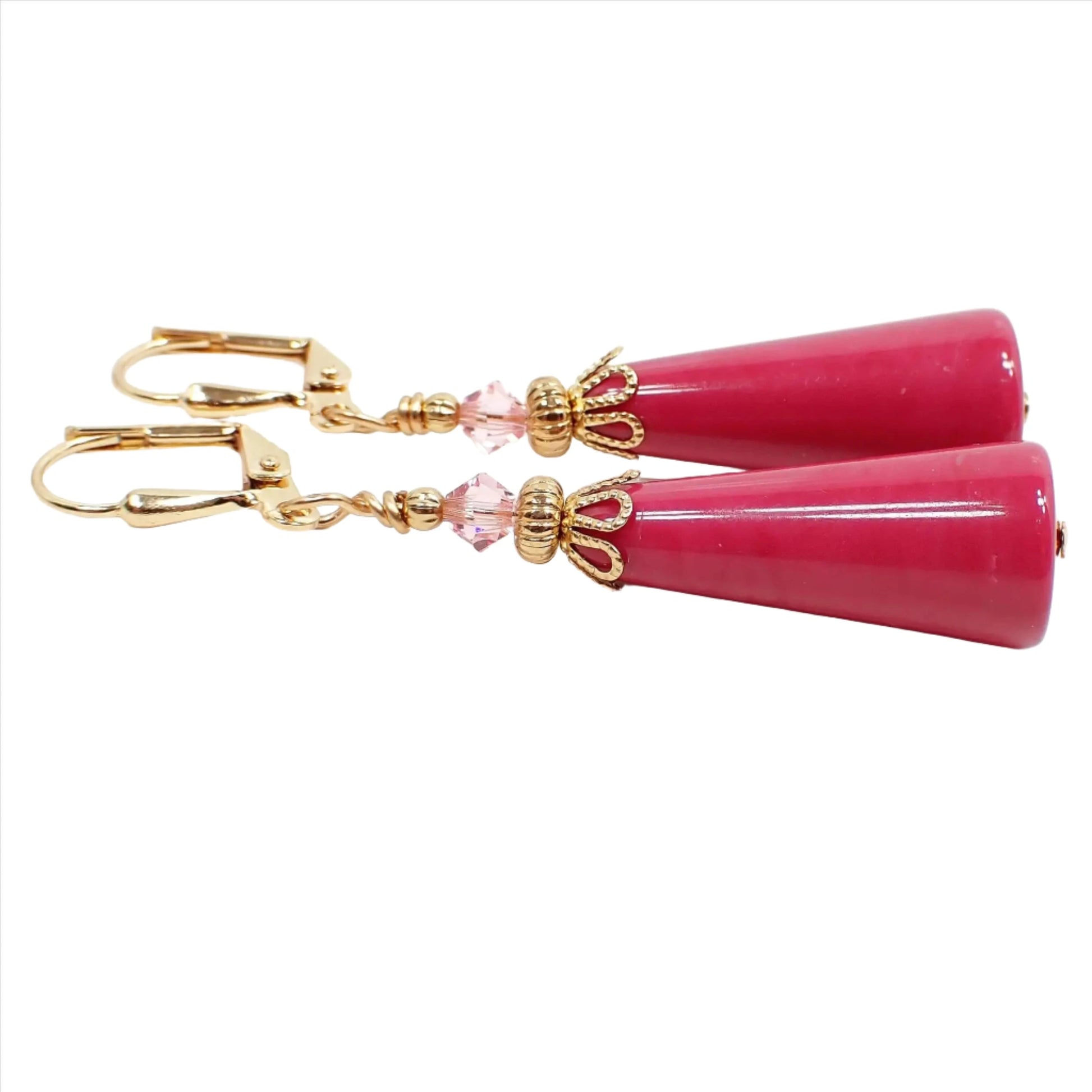 Side view of the handmade geometric cone earrings. The metal is gold plated in color. There are light pink faceted glass crystal beads at the top. The bottom beads are vintage lucite beads in a raspberry pink color.