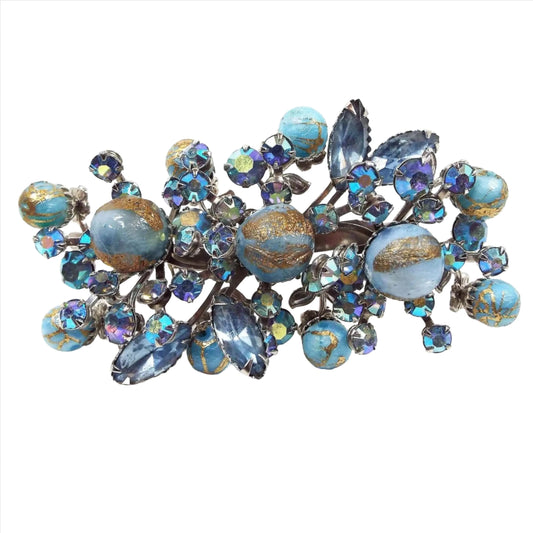 Front view of the 1950's Mid Century vintage rhinestone and beaded brooch pin. The metal is silver tone in color. This large brooch has a spray design with blue marquis rhinestones, ab blue round rhinestones, and textured round blue beads that have metallic gold lines painted on them.